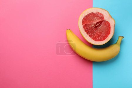 Banane und die Hälfte der Grapefruit auf farbigem Hintergrund, flach liegend mit Platz für Text. Sexualkonzept