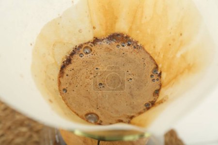 Photo for Paper filter with aromatic drip coffee in glass chemex coffeemaker, closeup - Royalty Free Image