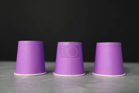 Shell game. Three purple cups on grey marble table