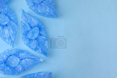 Photo for Medical shoe covers on light blue background, flat lay. Space for text - Royalty Free Image