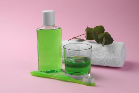 Foto de Composición con enjuague bucal fresco en botella, vidrio y cepillo de dientes sobre fondo rosa, primer plano - Imagen libre de derechos