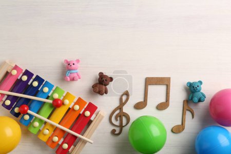 Téléchargez les photos : Concept de chanson de bébé. Notes en bois, xylophone et jouets sur table, pose à plat. Espace pour le texte - en image libre de droit