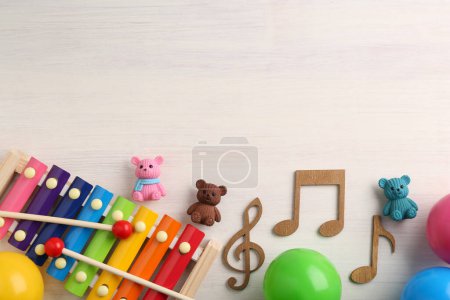 Téléchargez les photos : Concept de chanson de bébé. Notes en bois, xylophone et jouets sur table, pose à plat. Espace pour le texte - en image libre de droit