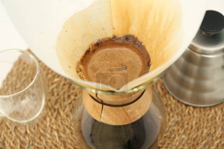 Papierfilter mit aromatischem Tropfkaffee in Glas-Chemex-Kaffeemaschine auf dem Tisch, Nahaufnahme