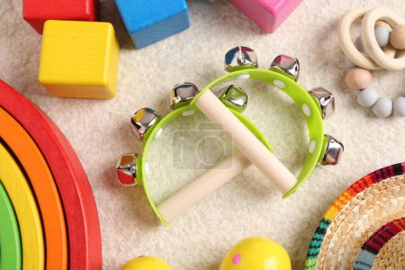 Baby song concept. Wooden tambourines and toys on beige carpet, flat lay