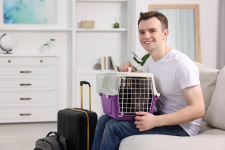 Reisen mit Haustier. Mann hält Tragetasche mit süßer Katze auf Sofa zu Hause, Platz für Text