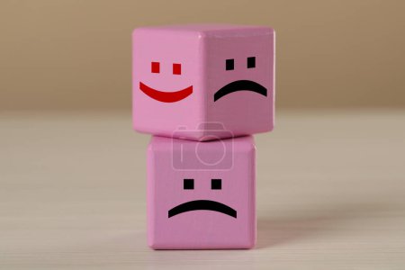 Photo for Pink cubes with sad and happy faces on wooden table - Royalty Free Image