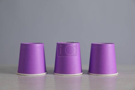Téléchargez les photos : Jeu de coquille. Trois tasses violettes sur la table lumineuse - en image libre de droit