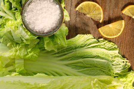 Fresh Chinese cabbage, salt and lemon on wooden table, flat lay