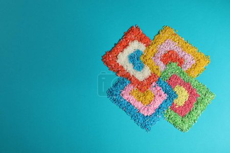 Diwali celebration. Colorful rangoli on light blue background, top view. Space for text