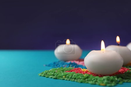 Téléchargez les photos : Fête de Diwali. Bougies brûlantes et rangoli coloré sur fond bleu clair, gros plan. Espace pour le texte - en image libre de droit