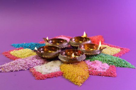 Diwali-Feier. Diya-Lampen und bunte Rangoli auf violettem Hintergrund