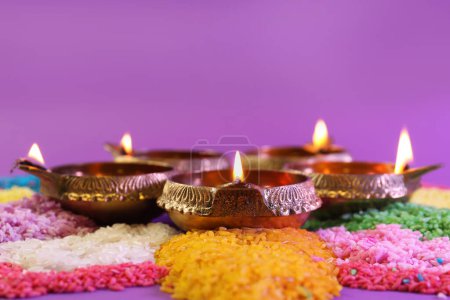 Téléchargez les photos : Fête de Diwali. Lampes Diya et rangoli coloré sur fond violet, gros plan - en image libre de droit