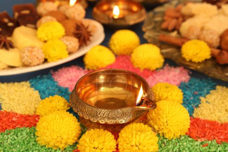 Téléchargez les photos : Fête de Diwali. Savoureux bonbons indiens, rangoli coloré et lampes diya sur la table, gros plan - en image libre de droit