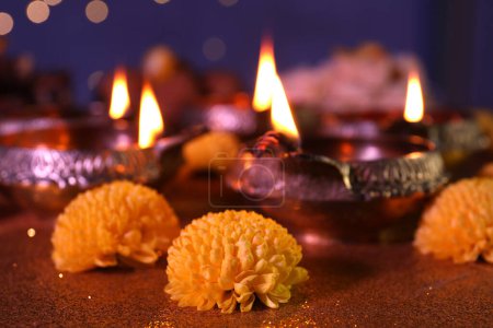 Téléchargez les photos : Fête de Diwali. Lampes Diya et fleurs de chrysanthème sur table brillante contre les lumières floues, gros plan - en image libre de droit