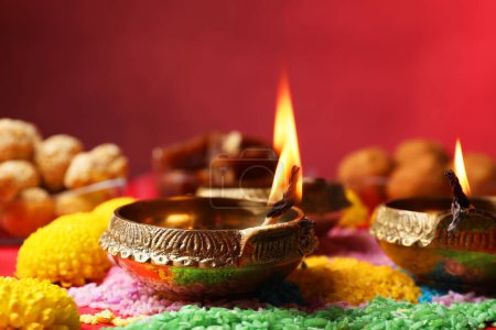 Téléchargez les photos : Joyeux Diwali. Lampes Diya, rangoli coloré et fleurs sur la table, gros plan - en image libre de droit
