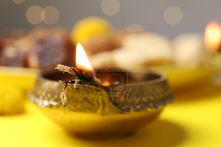 Téléchargez les photos : Joyeux Diwali. Lampe Diya sur table jaune contre les lumières floues, gros plan - en image libre de droit