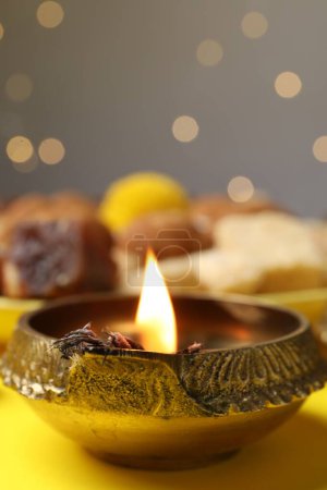 Téléchargez les photos : Joyeux Diwali. Lampe Diya sur table jaune contre lumières floues, gros plan. Espace pour le texte - en image libre de droit