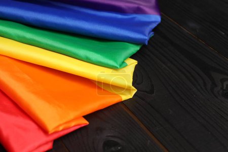 Rainbow LGBT flag on black wooden background, closeup