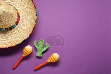 Sombrero mexicano sombrero, maracas y cactus de juguete sobre fondo violeta, puesta plana. Espacio para texto