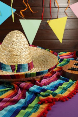 Chapeau sombrero mexicain, ukulélé et poncho sur table violette, gros plan