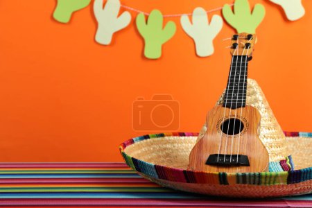 Chapeau sombrero mexicain et ukulélé sur la table de couleur, gros plan. Espace pour le texte
