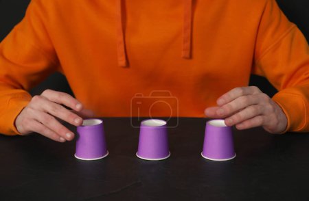 Man playing shell game at black table, closeup