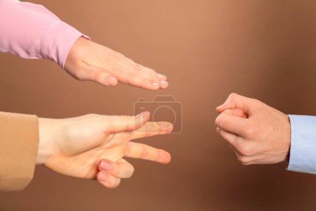 Photo for People playing rock, paper and scissors on brown background, closeup - Royalty Free Image