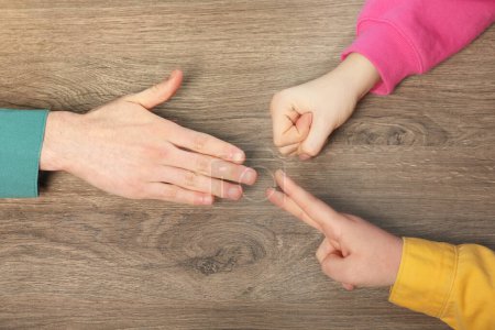 Photo for Closeup of people playing rock, paper and scissors on wooden background, top view - Royalty Free Image