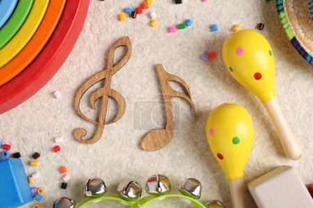 Foto de Concepto de canción de bebé. Notas de madera, instrumentos musicales para niños y juguetes en alfombra beige, puesta plana - Imagen libre de derechos