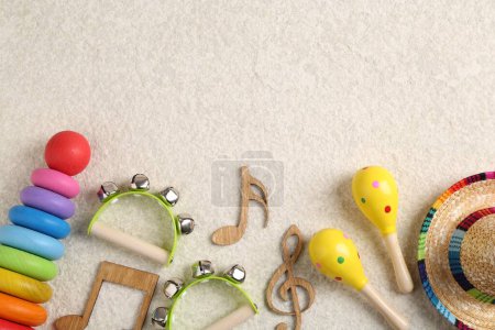 Concepto de canción de bebé. Notas de madera, instrumentos musicales para niños y juguetes en alfombra beige, puesta plana. Espacio para texto