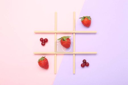 Tic tac toe game made with berries on color background, top view