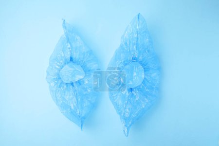 Pair of medical shoe covers on light blue background, top view