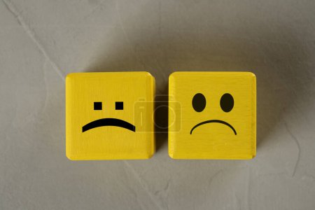 Photo for Yellow cubes with sad faces on grey table, top view - Royalty Free Image