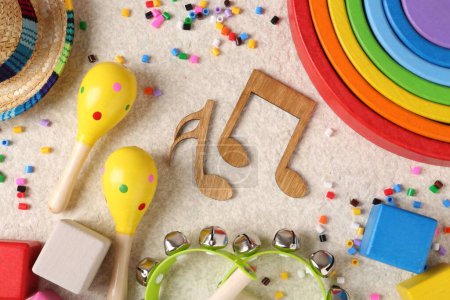 Concepto de canción de bebé. Notas de madera, instrumentos musicales para niños y juguetes en alfombra beige, puesta plana