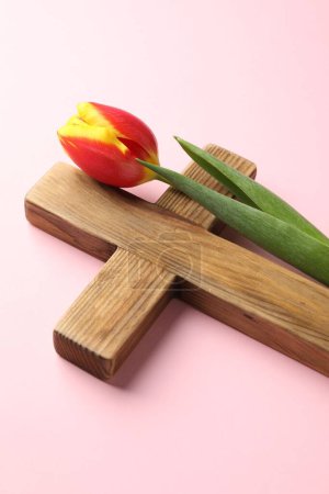 Photo for Easter - celebration of Jesus resurrection. Wooden cross and tulip on pink background, closeup - Royalty Free Image