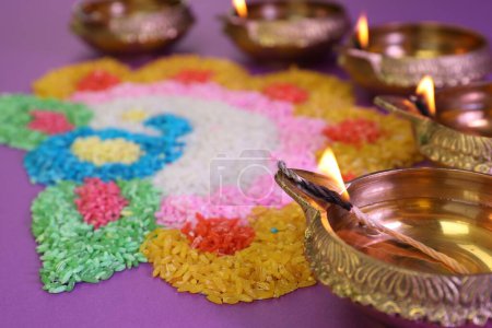 Téléchargez les photos : Fête de Diwali. Lampes Diya et rangoli coloré sur fond violet, gros plan - en image libre de droit