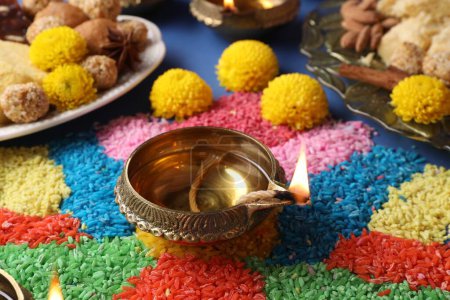 Diwali celebration. Diya lamps and colorful rangoli on table, closeup