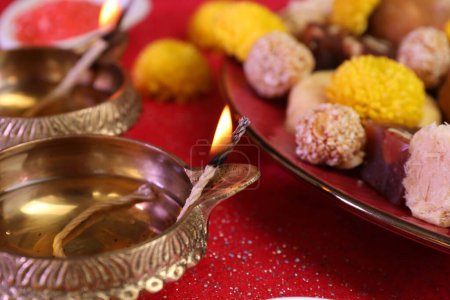 Téléchargez les photos : Fête de Diwali. Lampes Diya et savoureux bonbons indiens sur table rouge brillant, gros plan - en image libre de droit