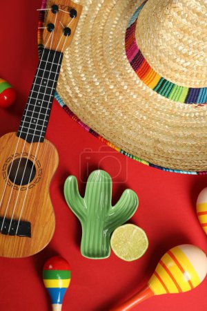 Composition plate avec chapeau sombrero mexicain et ukulélé sur fond rouge