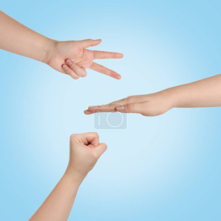 Photo for People playing rock, paper and scissors on light blue background, top view - Royalty Free Image