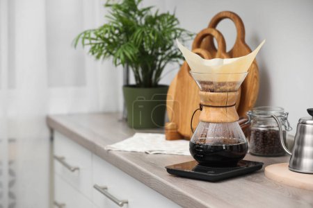Téléchargez les photos : Cafetière chemex en verre avec filtre en papier et café sur comptoir en bois dans la cuisine, espace pour le texte - en image libre de droit
