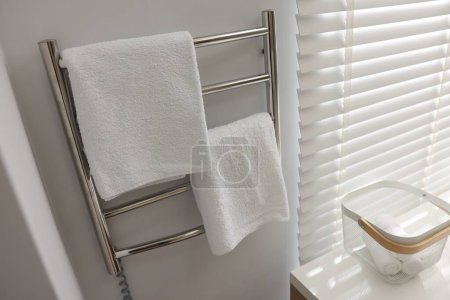 Photo for Heated rail with towels on white wall in bathroom - Royalty Free Image