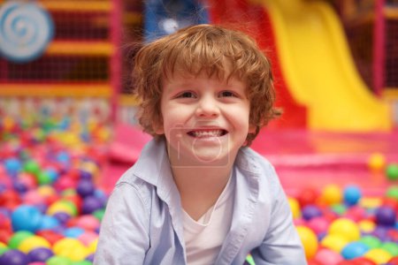 Joyeux petit garçon dans la fosse aux balles. Salle de jeux pour enfants