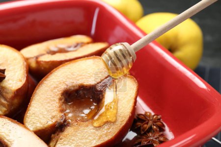 Gießen leckeren Honig auf gebackenen Quitten in Gericht auf dem Tisch, Nahaufnahme