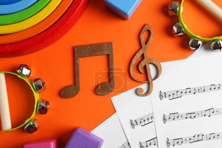 Foto de Herramientas para crear canciones para bebés. Composición plana con notas de madera y panderetas para niños sobre fondo naranja - Imagen libre de derechos