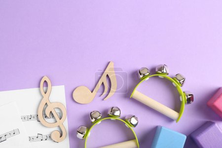Outils pour créer des chansons pour bébés. Composition plate avec des notes en bois et tambourins pour enfants sur fond violet
