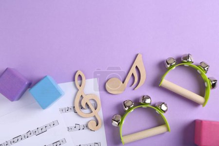 Foto de Herramientas para crear canciones para bebés. Composición plana con notas de madera y panderetas para niños sobre fondo violeta - Imagen libre de derechos