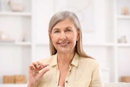 Menopausia, terapia hormonal sustitutiva. Mujer feliz sosteniendo píldora en casa