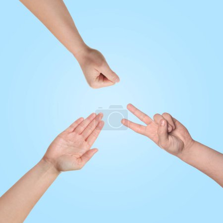 Photo for People playing rock, paper and scissors on light blue background, top view - Royalty Free Image